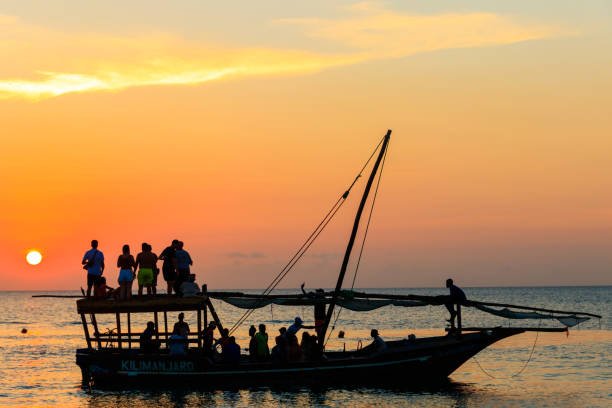 Traditional dhow sailing into sunset in Stone Town